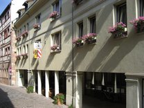 Fassade des Hotels Agneshof mit Blumenkästen an den Fenstern und einem Durchgang zur Straße