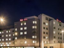Außenansicht des mehrstöckigen Hotels Ibis Nürnberg City am Plärrer bei Nacht mit beleuchteten Fenstern und rotem Ibis-Logo auf dem Dach