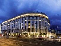 Großes, modernes Hotelgebäude mit abgerundeter Ecke und beleuchteten Fenstern bei Nacht