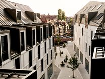 Blick von oben auf eine moderne Hotelanlage mit zwei mehrstöckigen Gebäuden und einem gepflasterten Innenhof mit Bäumen im Hotel Karl August im Augustinerhof
